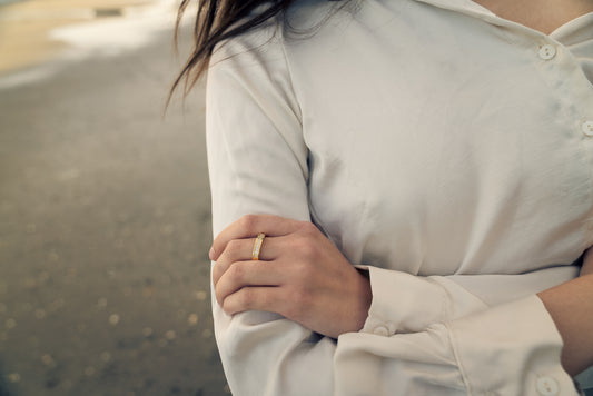 Women wearing a Half-Eternity Band gold ring with stones and light-colored shirt with a blurred background