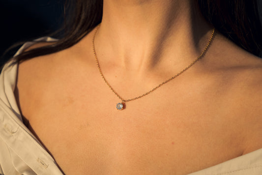 Gold plated Necklace with a cubic zirconia pendant worn by a person, with a soft focus on the background