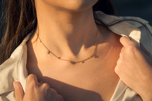 Close-up of a person wearing a delicate gold necklace with Cubic zirconia stones.