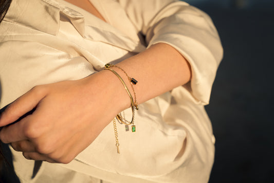 Close-up of a women's wrist with multiple bracelets on a neutral background