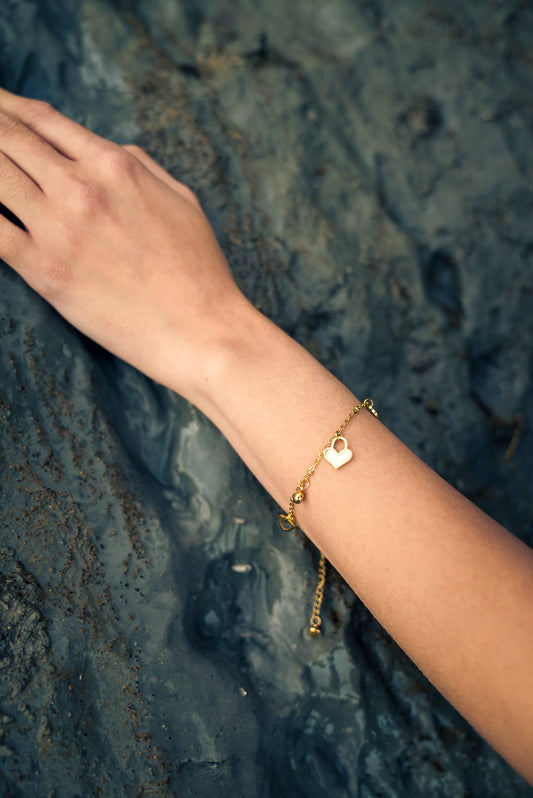 Hand wearing a gold bracelet on a textured dark surface