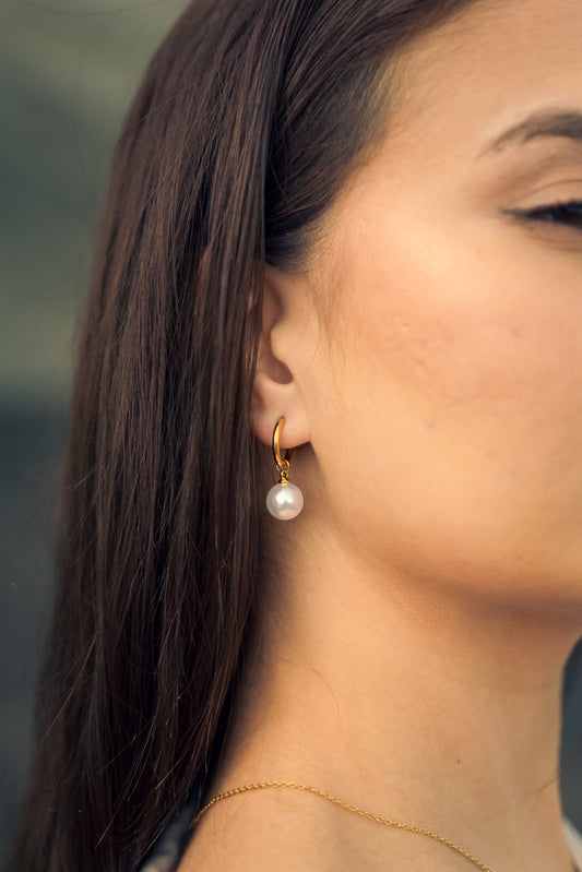 Close-up of a woman wearing a pearl earring with a blurred background