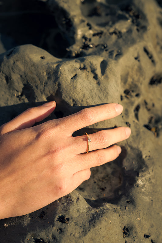 Hand with a solitaire Cubic zirconia stone ring on a textured surface