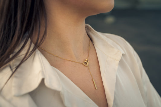 Close-up of a person wearing a gold necklace with a lock pendant.