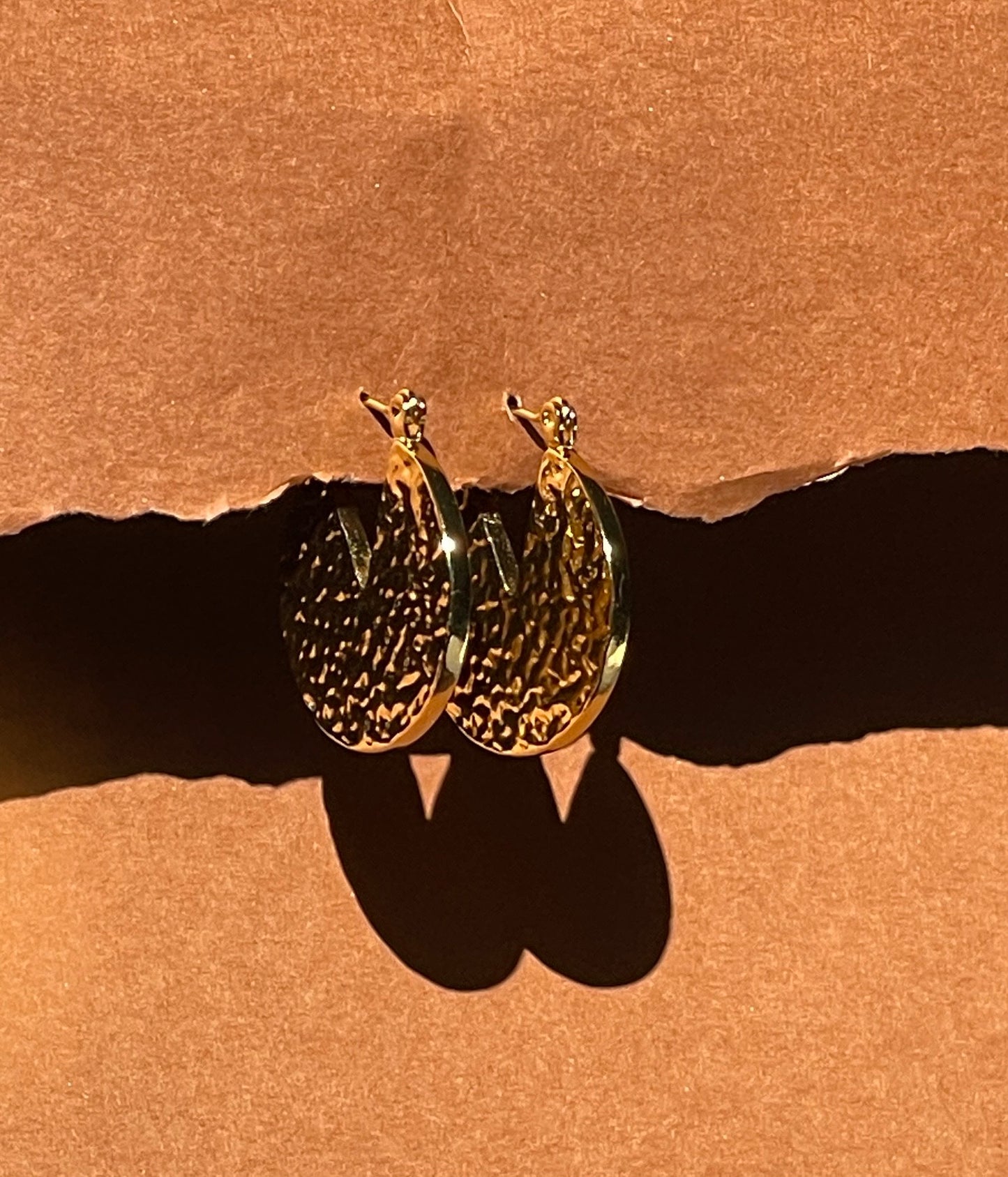 Gold Dune Hoops earrings on a brown background