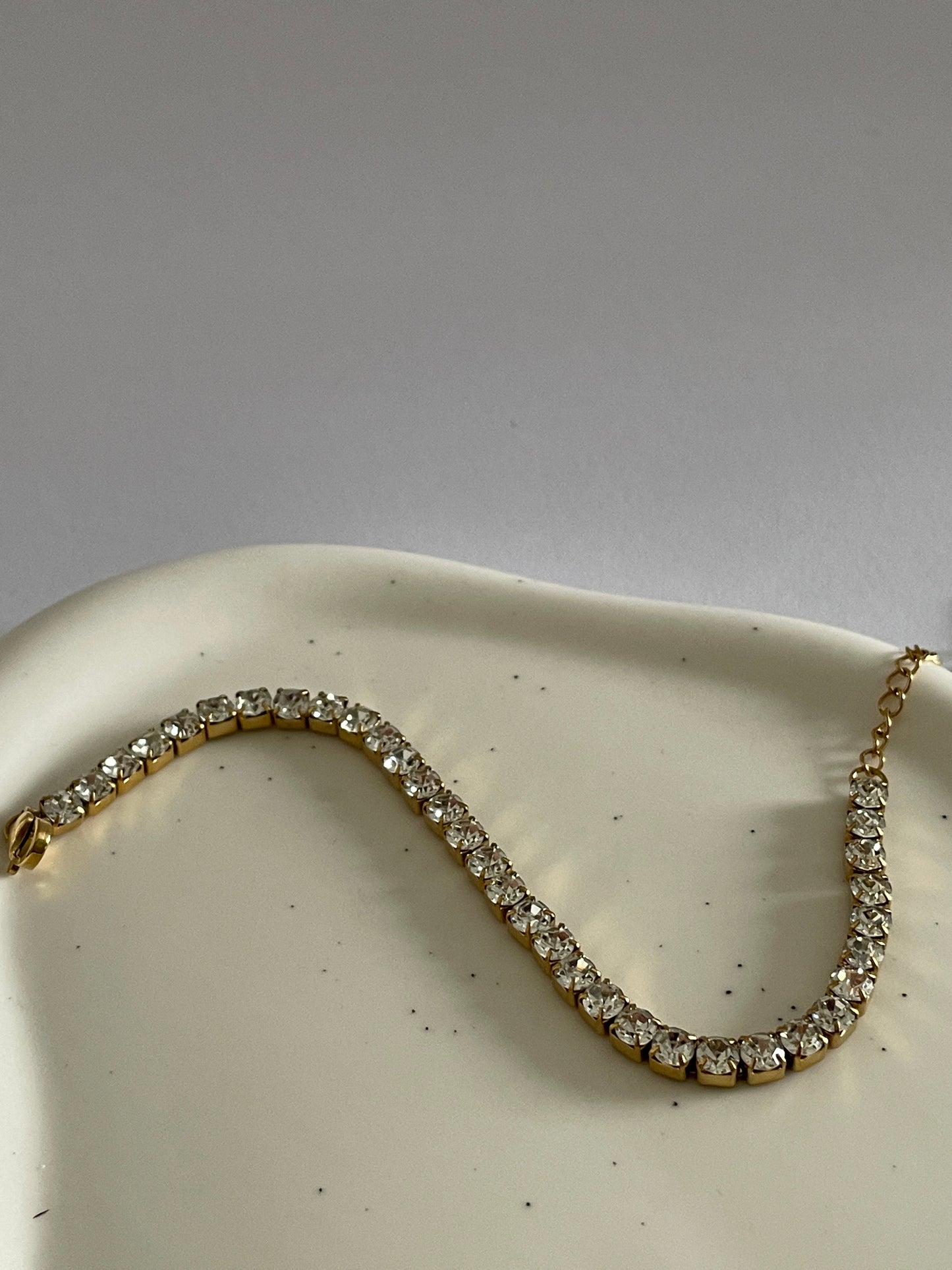 Gold Tennis bracelet with cubic zirconia stones on a white dish