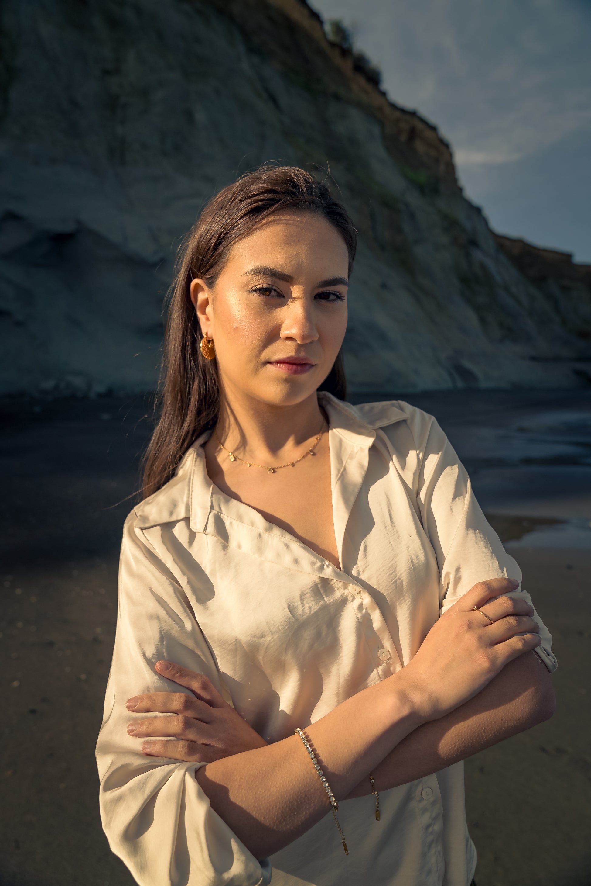 Woman standing on a beach wearing Tennis Bracelet with cliffs in the background