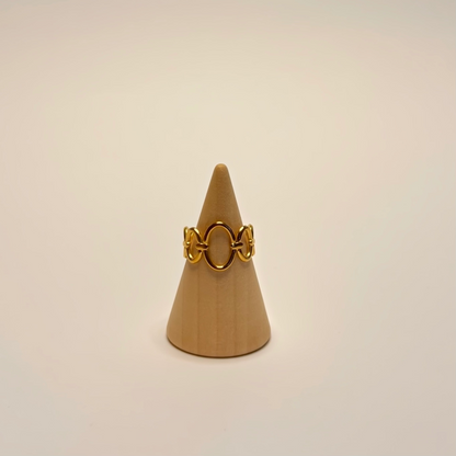 Gold ring on a beige cone-shaped stand against a beige background