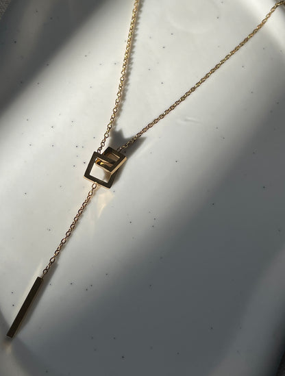Gold necklace with a pendant on a white surface